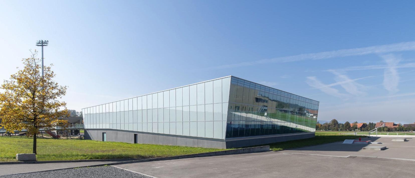 Gebäude einer modernen Sporthalle, davor ein Skateplatz