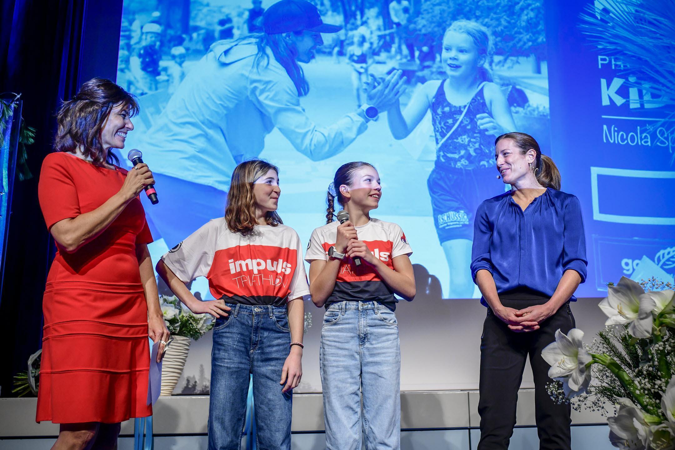 Sportpreis des Kantons Zürich 2022: Auf der Bühne stehen  von links die Moderatorin, zwei Mädchen des Triathlon-Clubs , welche am Abend gesungen haben, und Nicola Spirig
