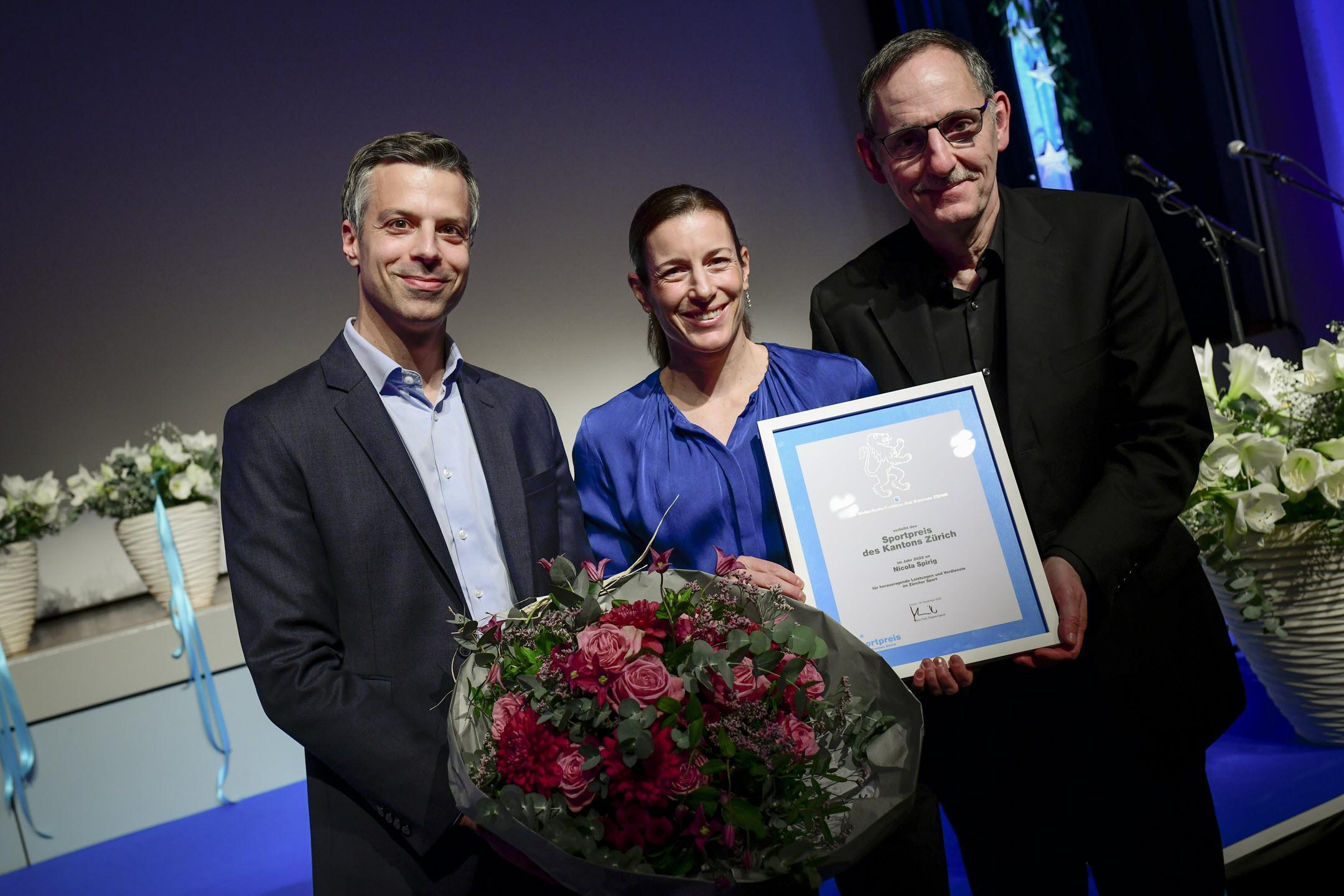 Sportpreis des Kantons Zürich 2022: Gemeindepräsident Michael Biber, Nicola Spirig und Mario Fehr posieren mit Blumenstrauss und Diplom