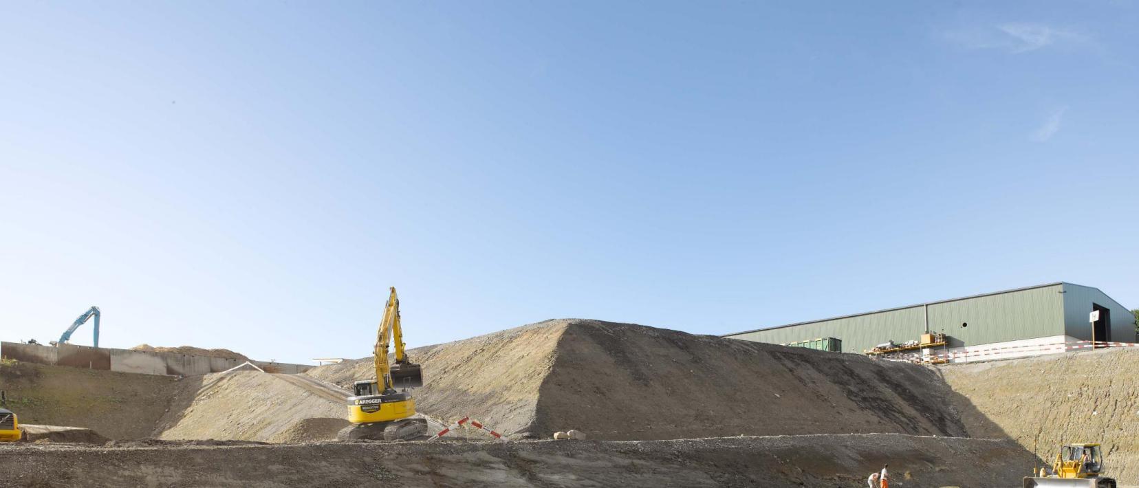 Ausschnitt aus einem Neubau einer Deponie für Schlacke aus Kehrichtverwertungsanlagen: Verschiedene Maschinen arbeiten an der Verdichtung der Deponiesohle