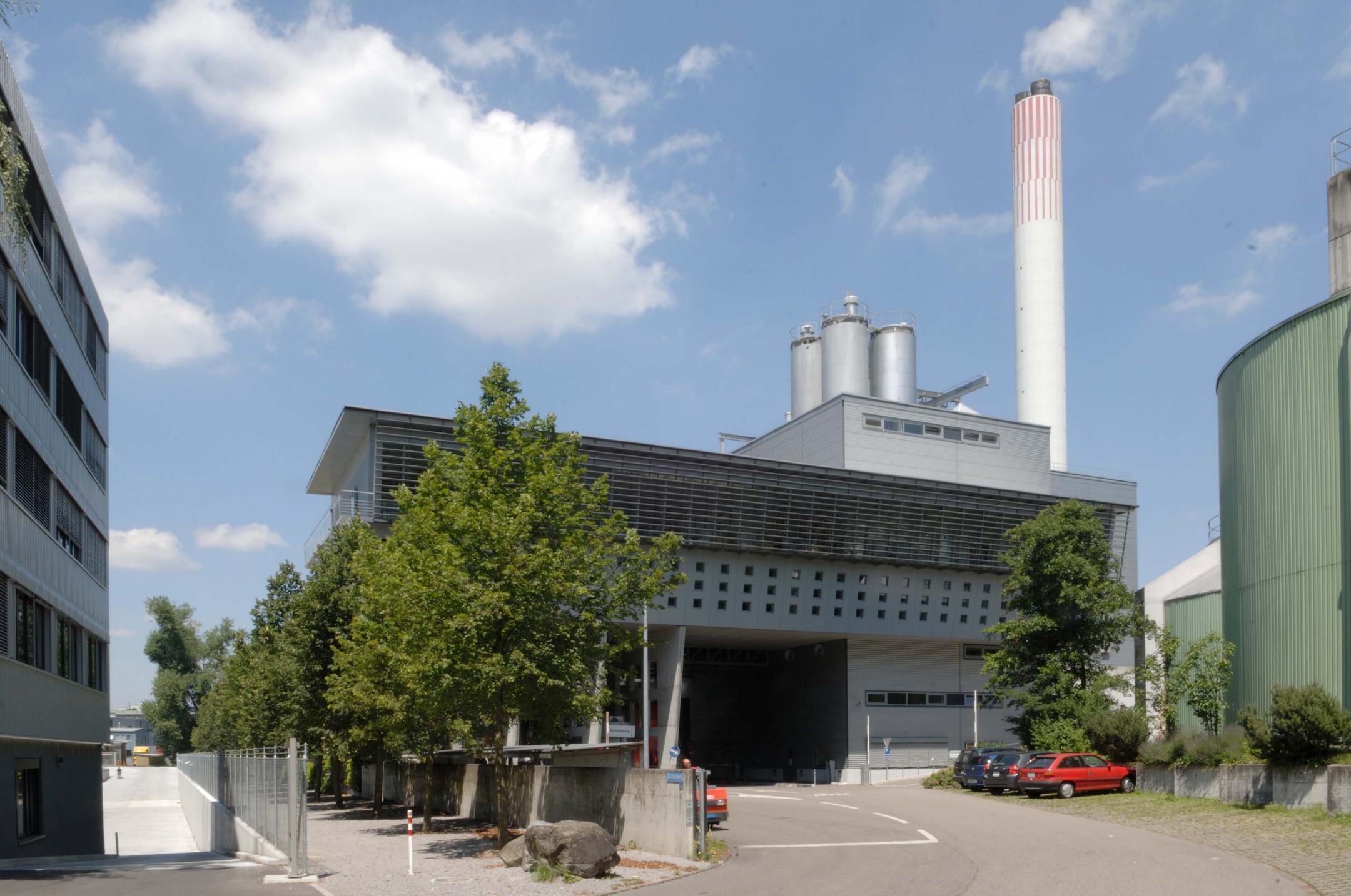 KVA Limmattal in Dietikon mit rauchendem Schornstein vor blauem Himmel.