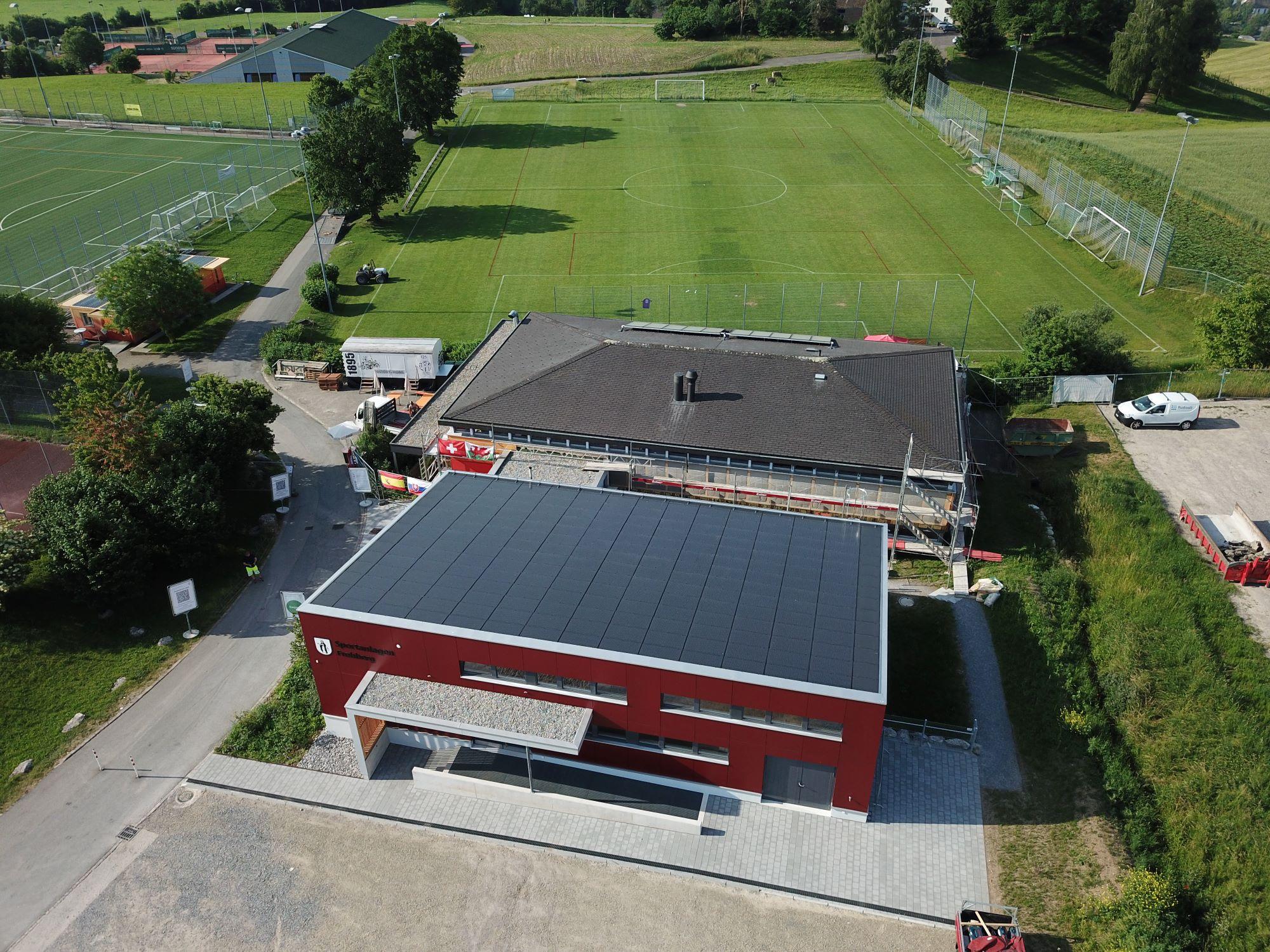 Eine grosse Sporthalle von oben fotografiert. Das Dach ist mit Solarzellen bedeckt. 
