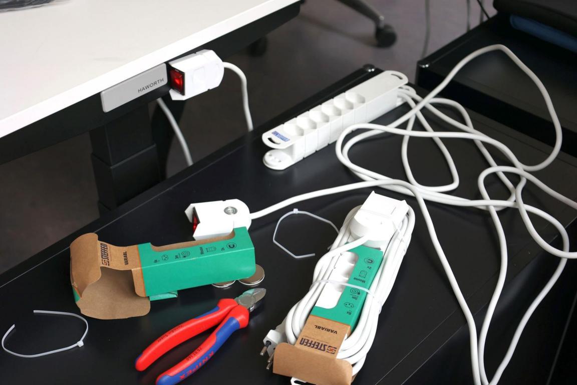 Auf einem Tisch liegen Steckerleisten und Strömmäuse sowie verschiedenes Werkzeug für die Installation. 