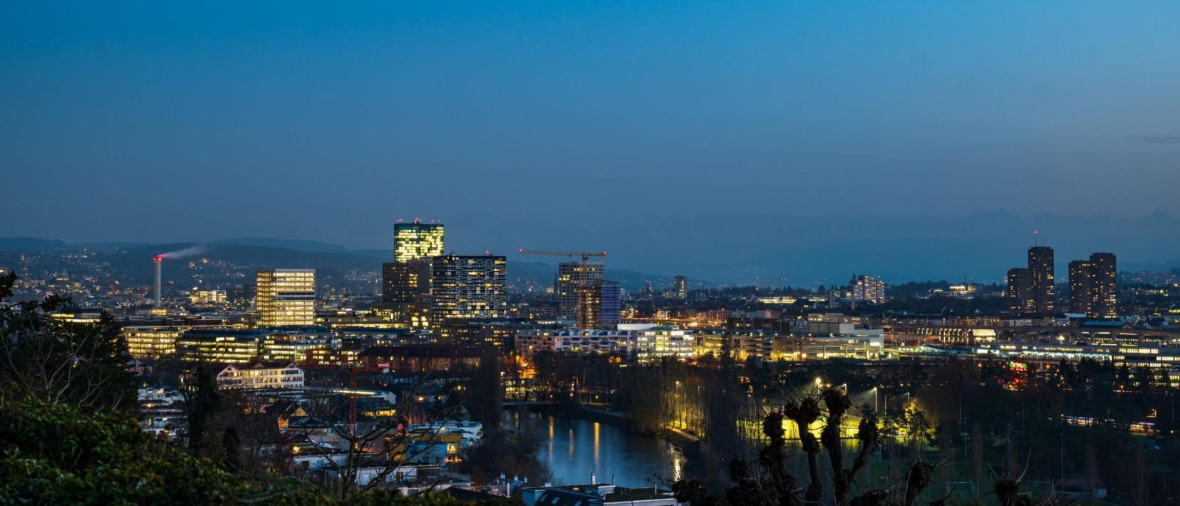 Beleuchtete Skyline von Zürich in der Dämmerung. 