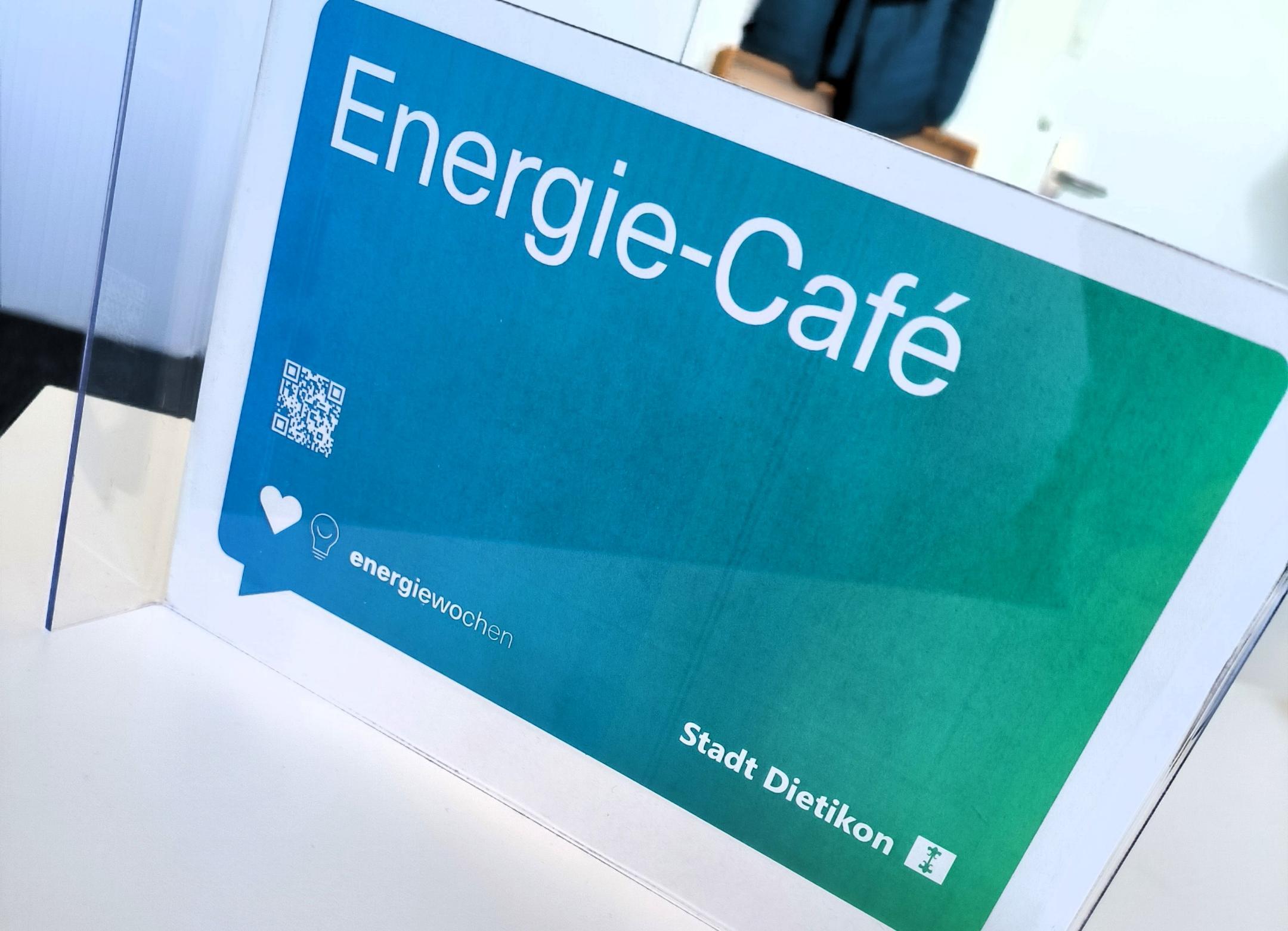 Ein Schild auf dem mit weisser Schrift auf blau-grünem Hintergrund die Worte Energie-Café stehen.
