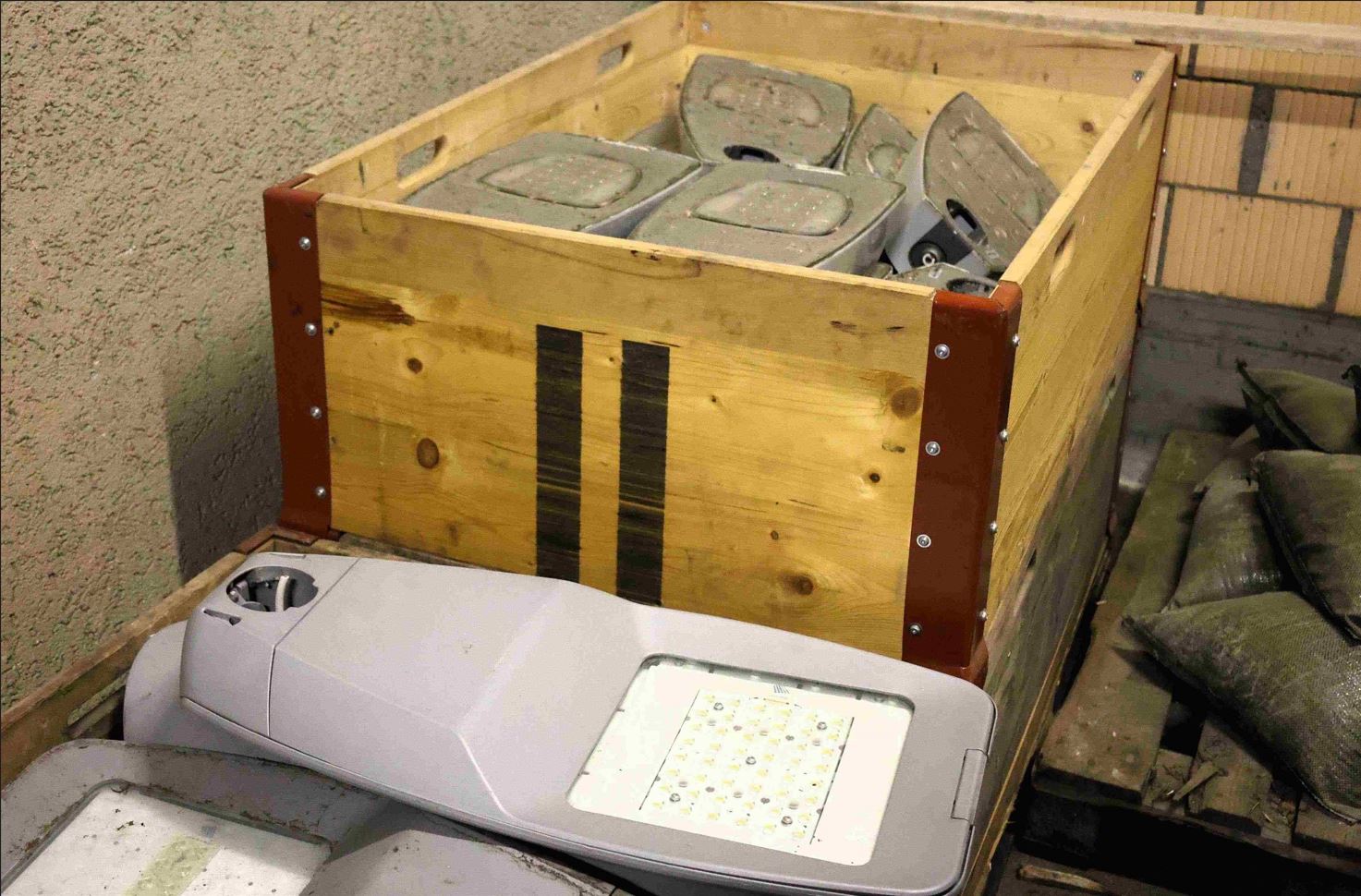 In zwei hölzernen Palettkisten sind neue Lampenköpfe zu sehen. Sie haben auf ihrer Unterseite eine grosse Leuchtfläche mit LED-Lichtern.