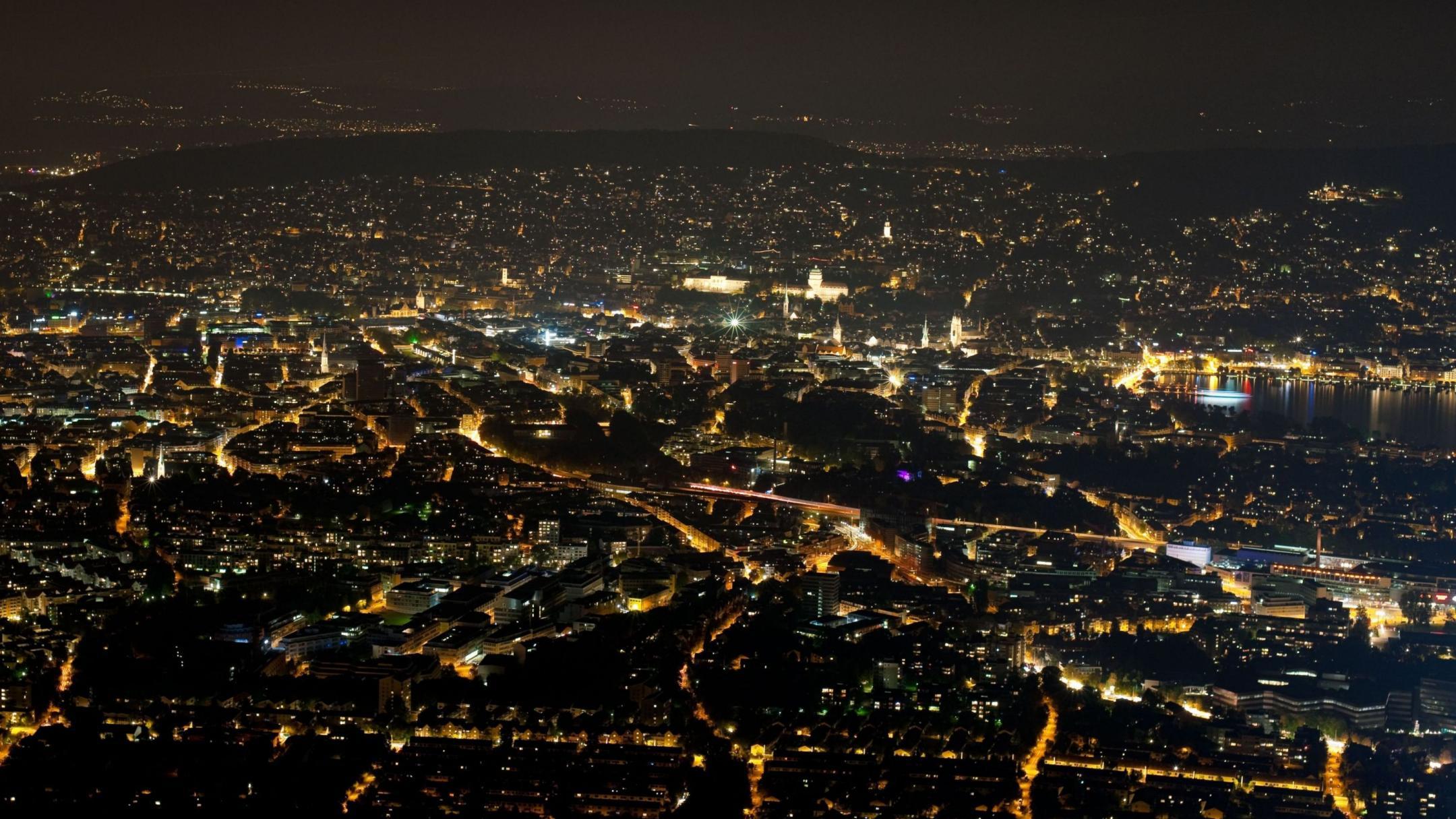 Blick von einem erhöhten Standpunkt aus auf die Lichter der Stadt Zürich bei Nacht. 