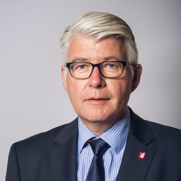 Das Portraitfoto von Thomas Peter zeigt einen Herren im dunklen Anzug mit Brille und grauen Haaren. 
