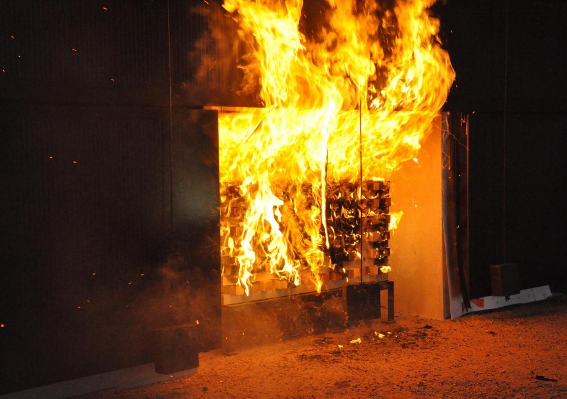 Starke Flammen lodern aus einer brennenden Holzkrippe während eines Brandversuchs, um die Ausbreitung von Feuer zu untersuchen.