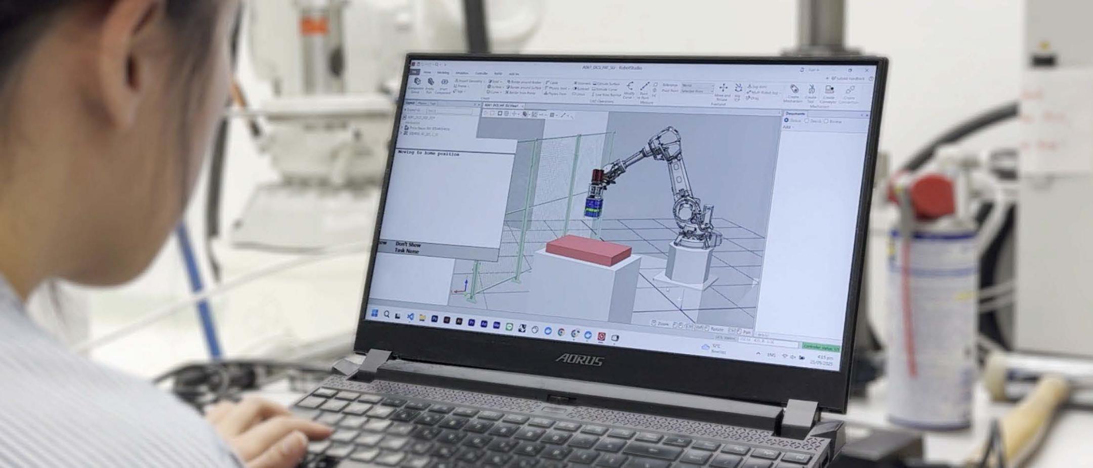 Eine Frau sitzt vor einem Laptop. Auf dem Laptop ist ein Roboteram zu sehen.