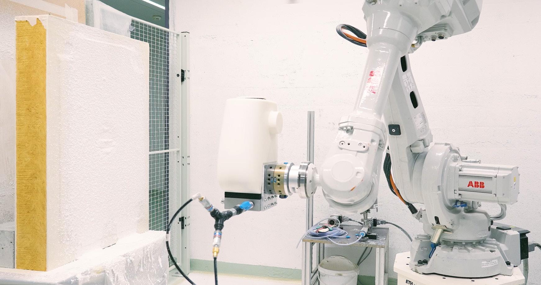 Ein Roboterarm spritzt Material auf die Leichtbauplatte