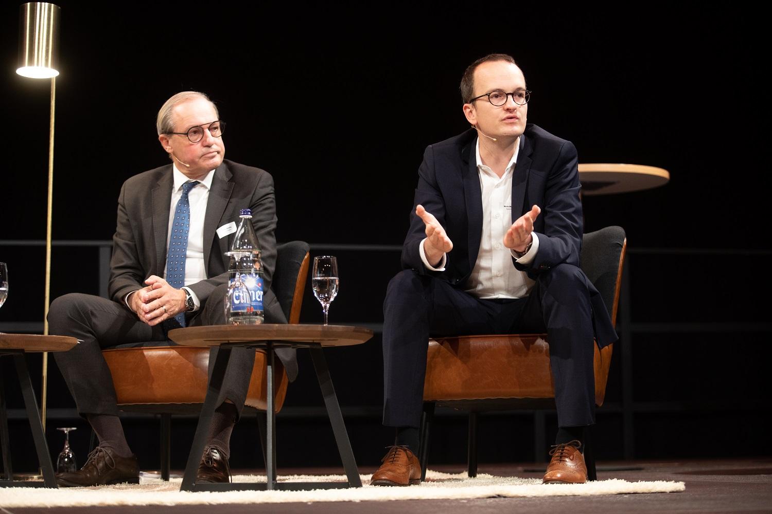 Bühnenszene. Baudirektor Martin Neukomm spricht im Rahmen der Podiumsdiskussion. Neben ihm sitzt der Präsident der Gemeindepräsidien, Jörg Kündig.