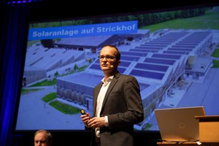 Martin Neukom bei seinem Inputreferat, Projektion im Hintergrund zeigt Solaranlage auf Strickhof-Gebäude