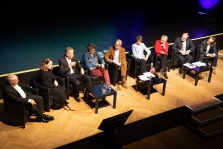 Die neun Personen aus Politik, Verwaltung und Fachthemen sitzen nebeneinander in Sesseln auf einer Bühne
