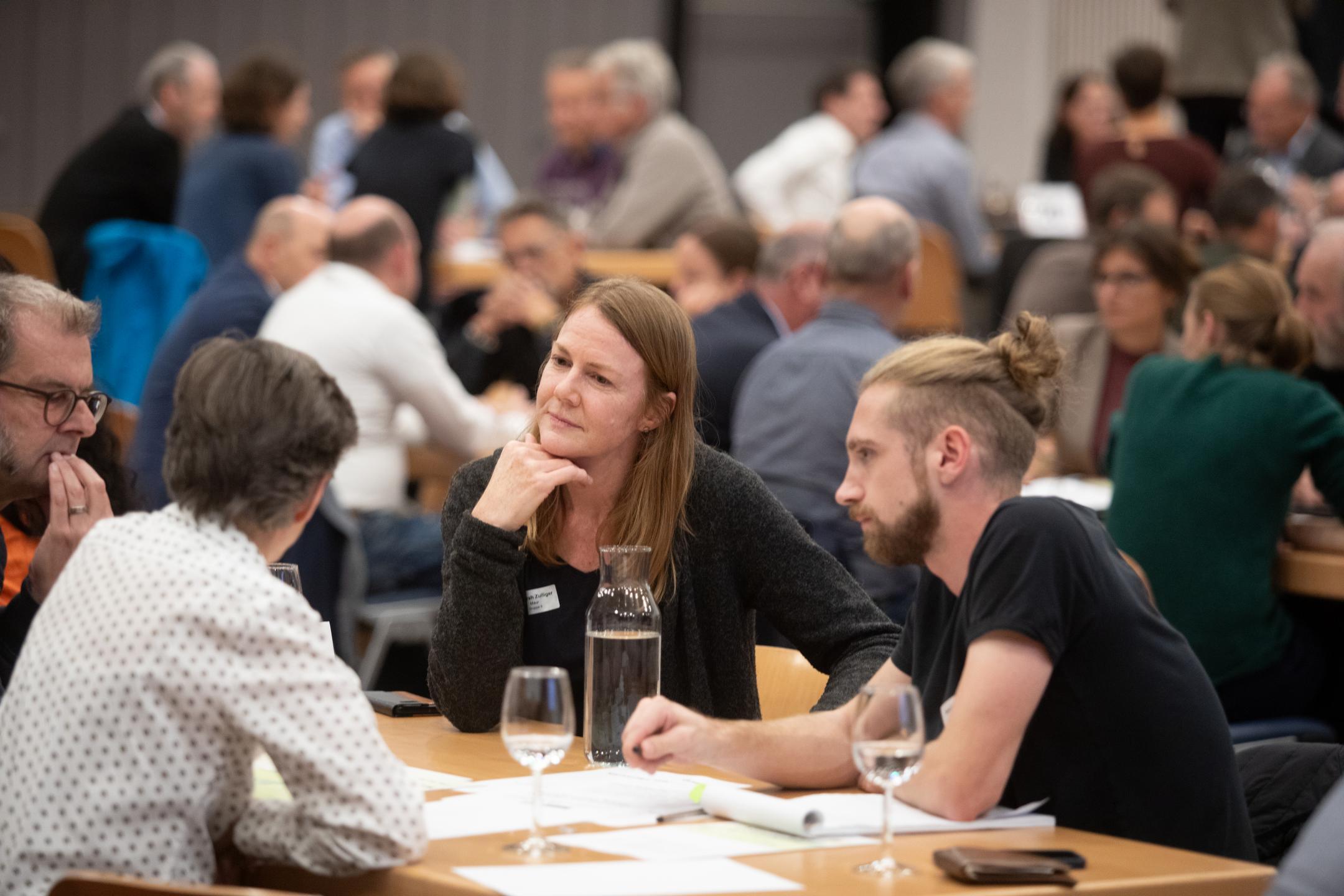 Teilnehmende diskutieren an Tischen