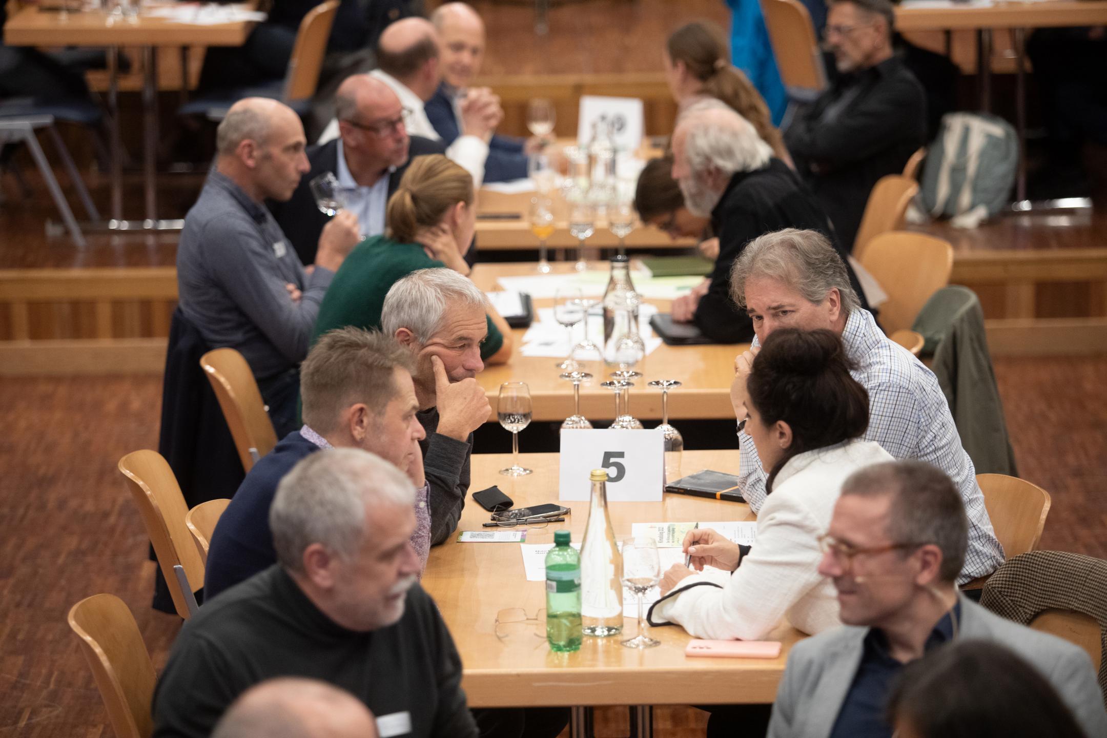 Teilnehmende diskutieren an Tischen