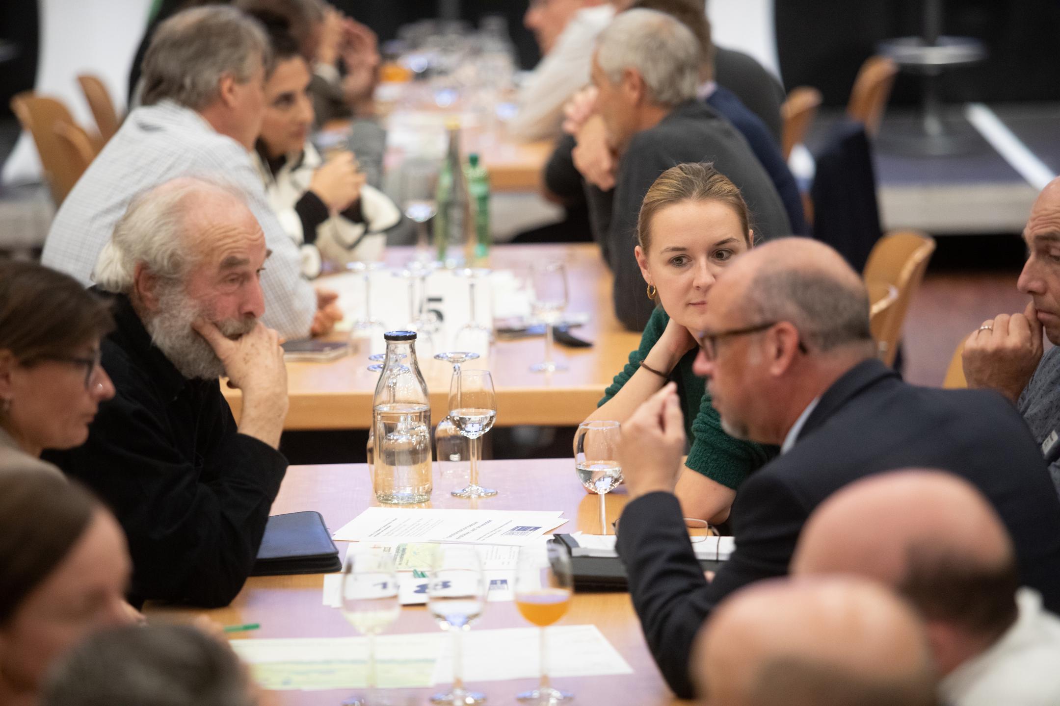 Teilnehmende diskutieren an Tischen