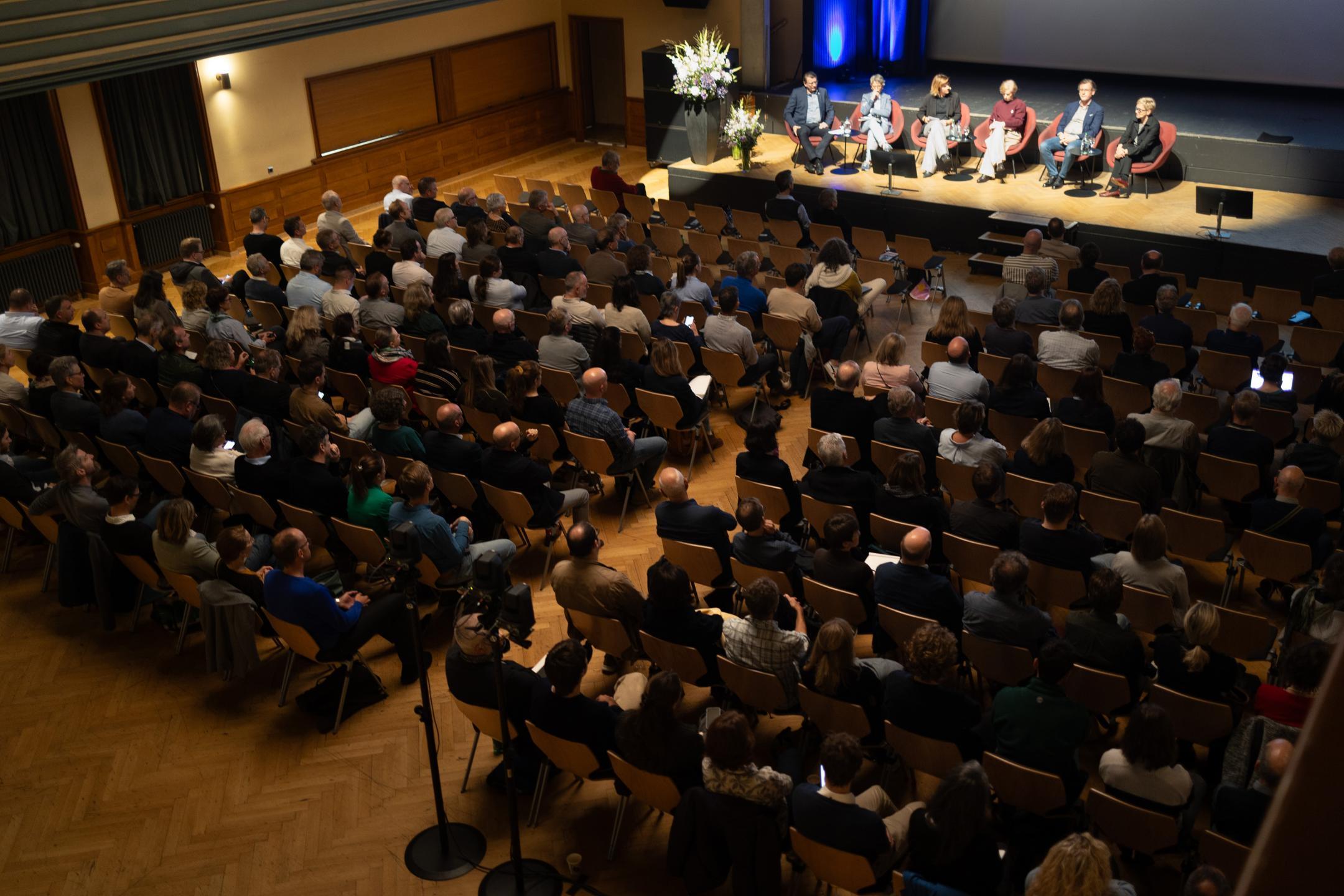 Blick von oben auf Publikum, im hinteren Bereich des Bildes ist Podium zu sehen