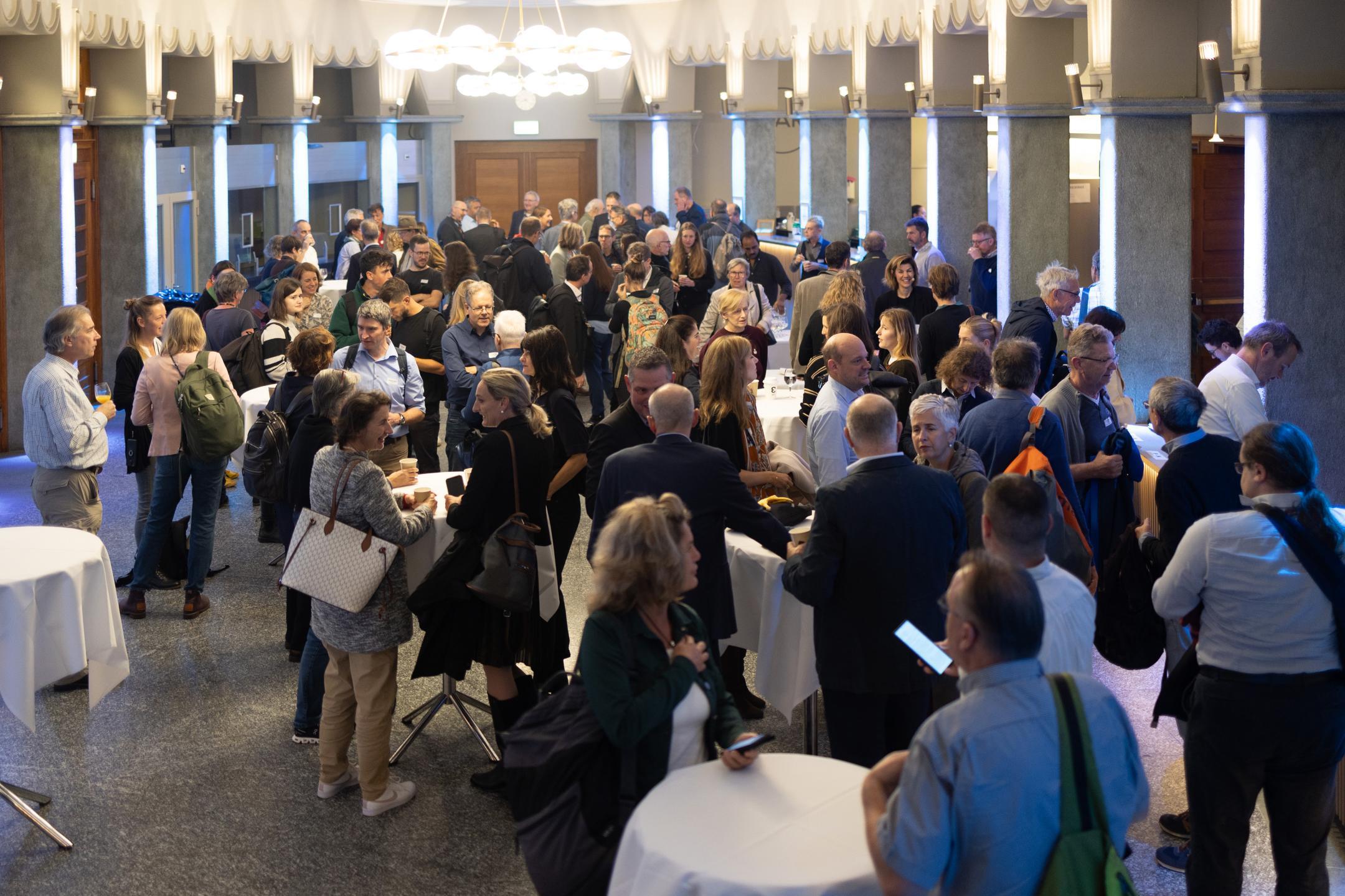 Mehrere Personen stehen im Foyer und unterhalten sich