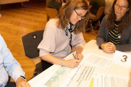 Teilnehmerin eines Workshops schreibt auf ein A3-Blatt