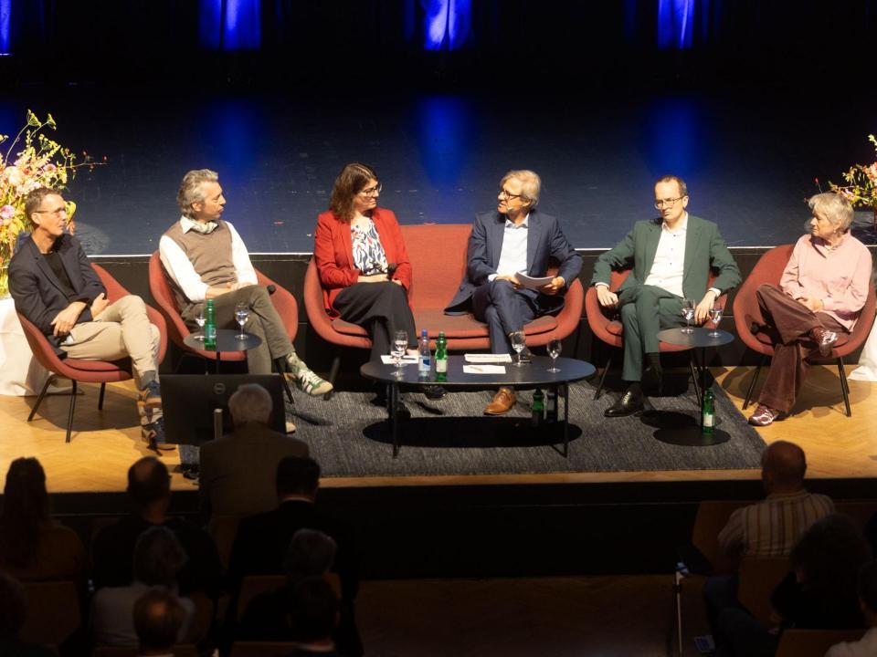 Sechs Personen sitzen für die Podiumsdiskussion auf roten Stühlen auf der Bühne: Michael Hermann (Sotomo), Thomas Ziltener (Co-Präsident VZGV), Monika Keller (Präsidentin GPV), Michael Emmenegger, Moderation, Regierungsrat Martin Neukom und Regierungsrätin Jacqueline Fehr.