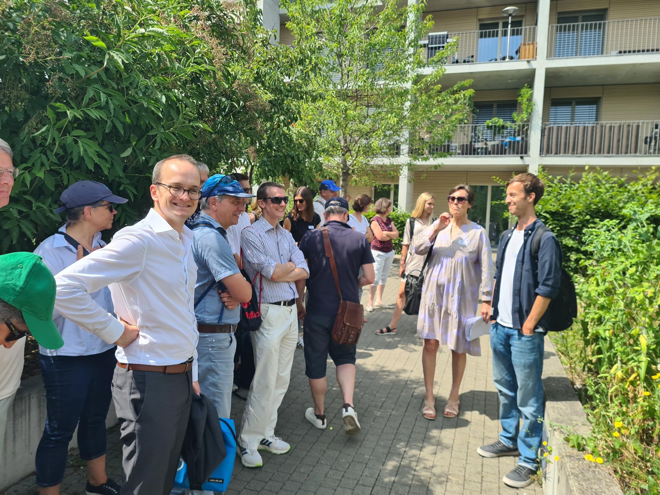 Teilnehmende stehen in Siedlung und hören der Stadtplanerin zu
