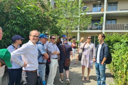 Teilnehmende stehen in Siedlung und hören der Stadtplanerin zu