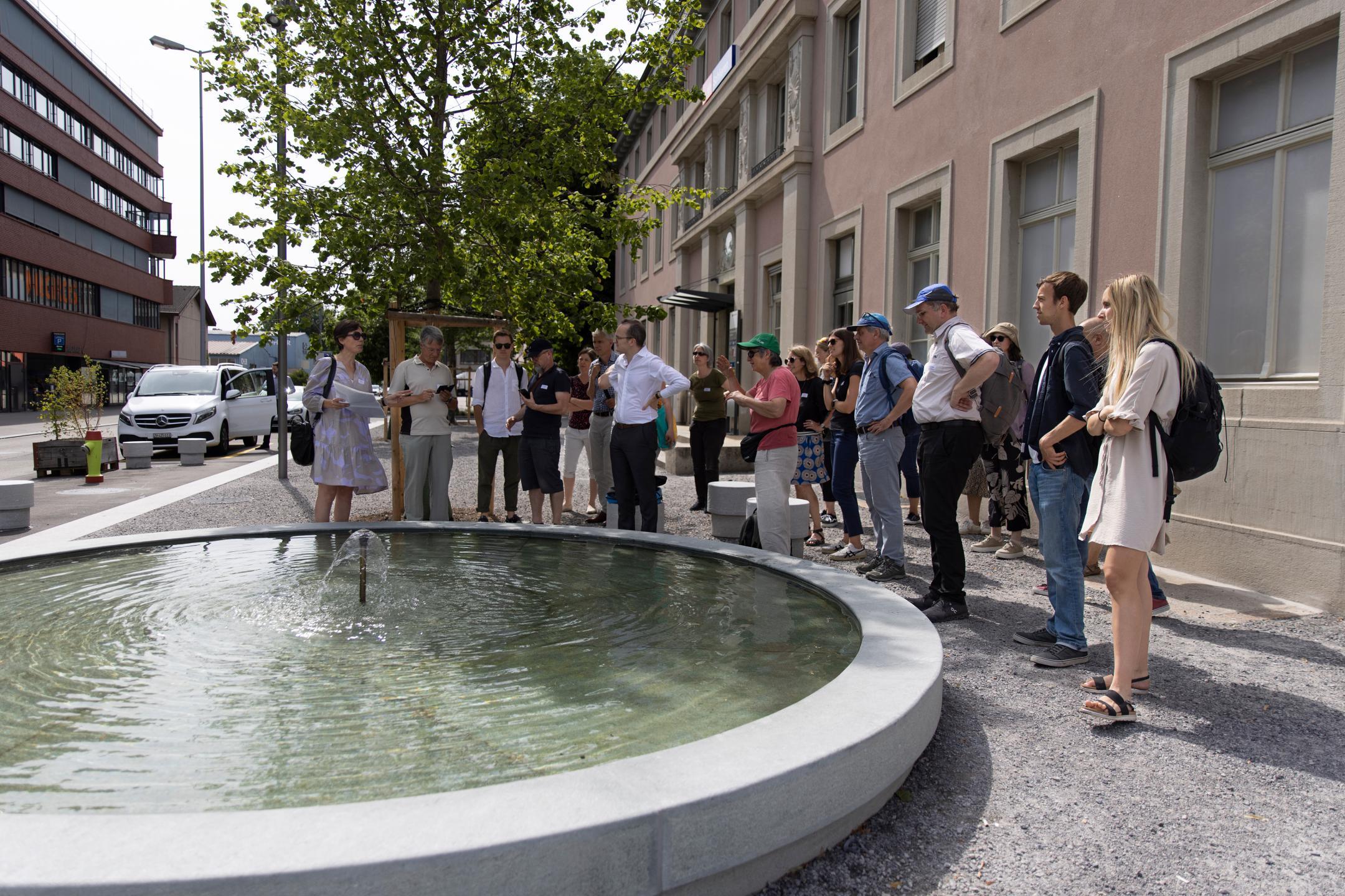 Teilnehmende stehen um Brunnen bei Bahnhof Schlieren