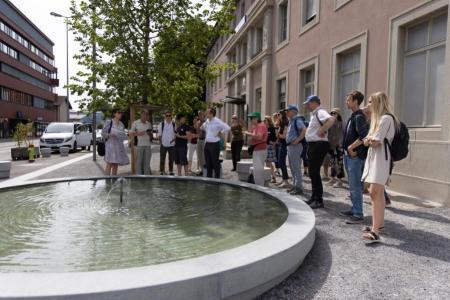 Teilnehmende stehen um Brunnen bei Bahnhof Schlieren