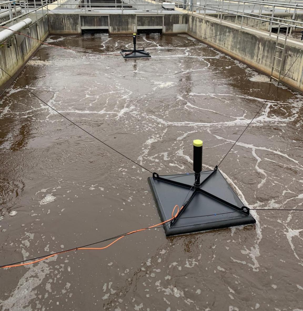 Klärbecken mit zwei viereckigen Messhauben, die drauf schwimmen.