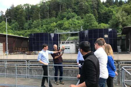 zwei Personen zeigen den Teilnehmenden einen Messbehälter