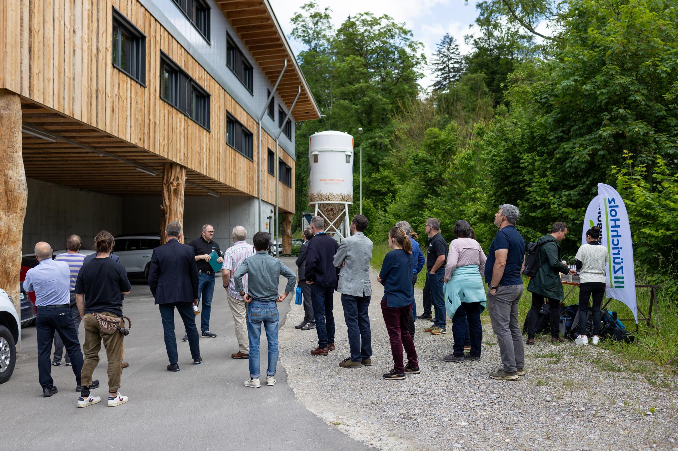 Teilnehmende vor dem Neubau aus Holz