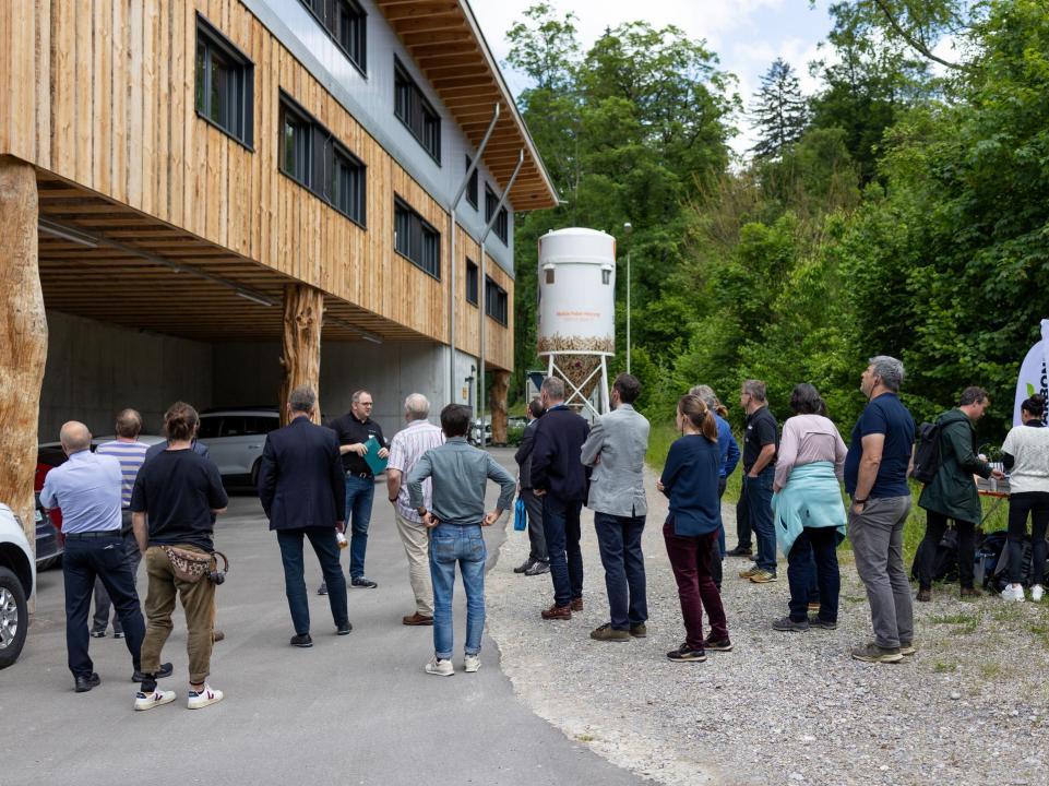 Teilnehmende vor dem Neubau aus Holz