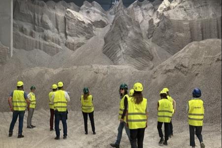 Teilnehmende des Klimadialogs 2025 in Leuchtwesten und mit Helmen auf dem Kopf besichtigen eine Halle mit recycelten Bauabfällen im  Aufbereitungszentrum der Eberhard Unternehmungen.