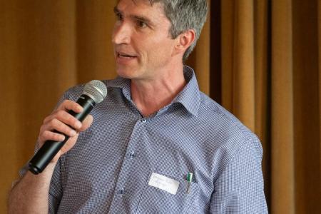 Benjamin Buser sprechend mit einem Mikrofon und Notizen in der Hand.