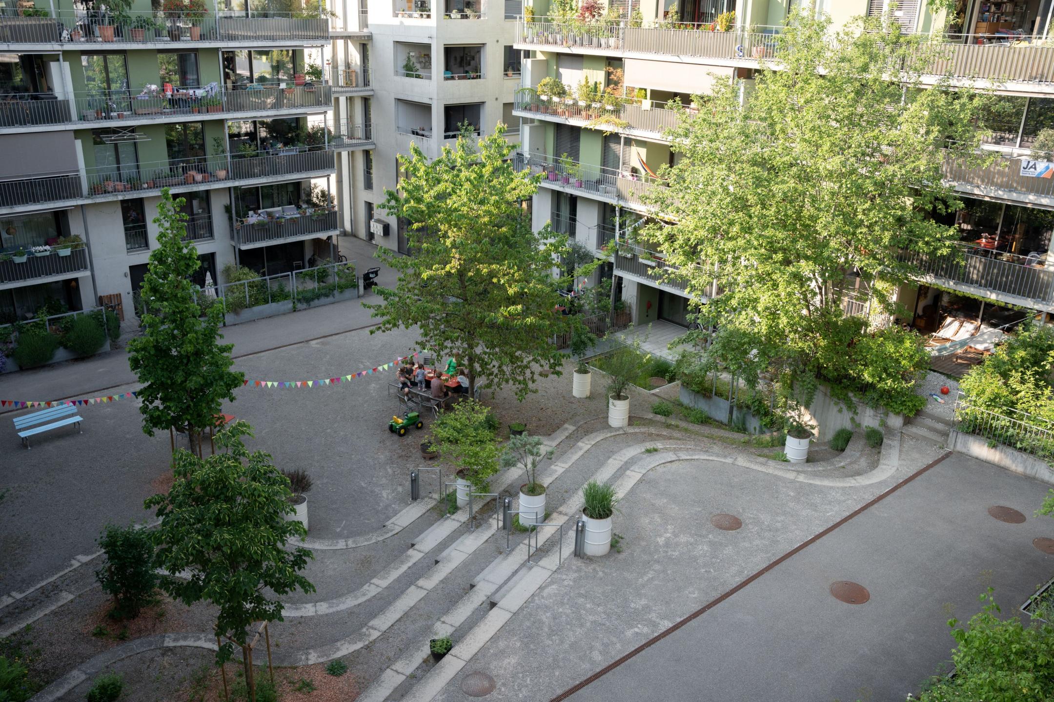 Der Innenhof der Siedlung besteht aus einem Kiesbelag. Es hat eine grosse Treppe mit grossen Stufen zum Sitzen, welche die unterschiedliche Geländehöhe miteinander ausgleicht.  Es hat vier mittelgrosse Bäume. Am Rand des Innenhofs hat es ein begrüntes Retentionsbecken. 