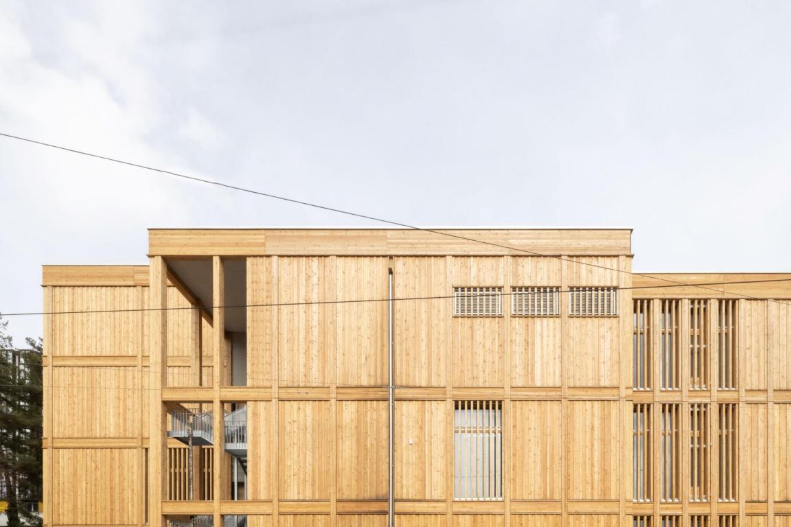 Das aus Holz gebaute Sporthallenprovisorium Gloriarank der Uni Zürich. Man sieht die Holzfassade der oberen zwei Stockwerke inkl. mehrerer Fenster