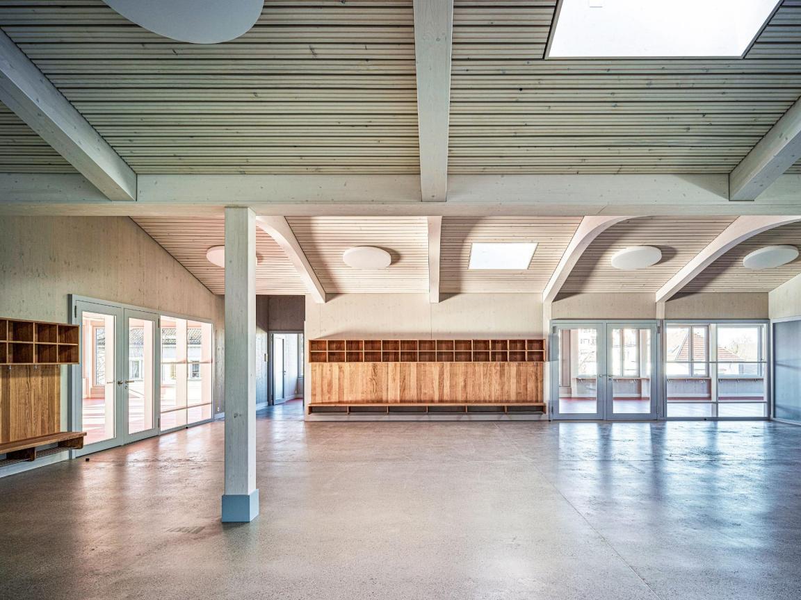 Blick in einen grossen, hellen Raum des Schulhauses Lätten in Fällanden. Gut sichtbar sind verschiedene Holzmodule und Holzkonstruktionen.