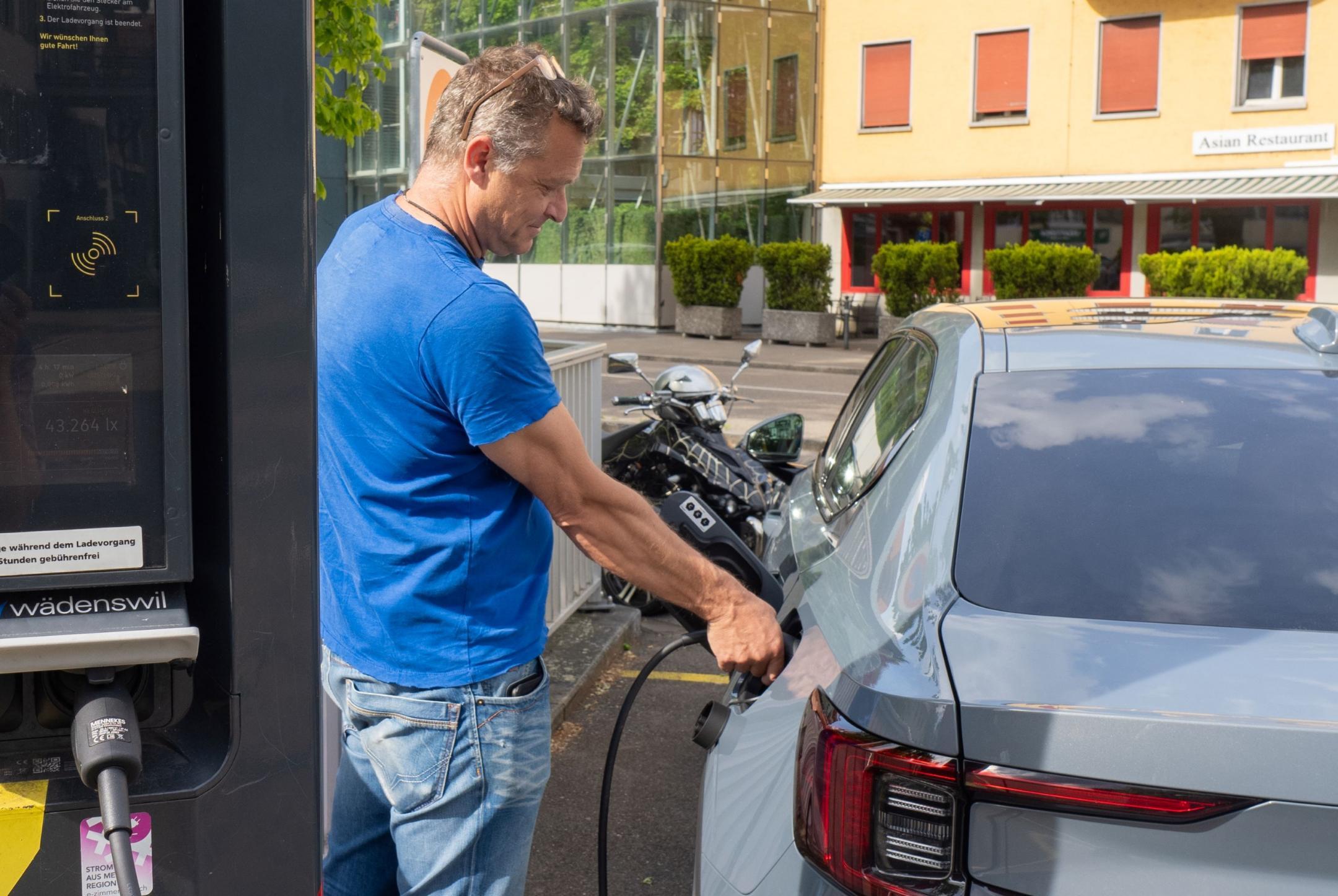 Ein Mann lädt ein Elektroauto an einer Ladestation.