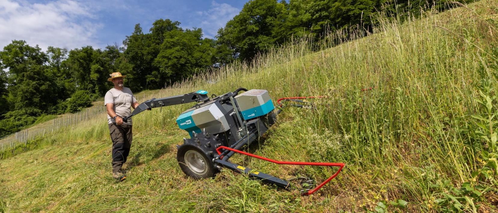 Ein Mitarbeiter der Fachstelle Naturschutz mäht mit dem elektrischen Motormäher ein steiles Wiesenbord.
