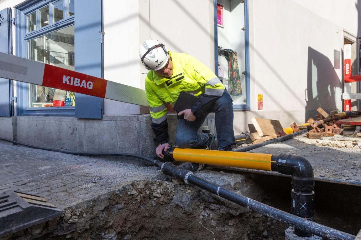 Ein Bauarbeiter passt ein Rohr für eine Gasleitung in einer Baugrube an. 