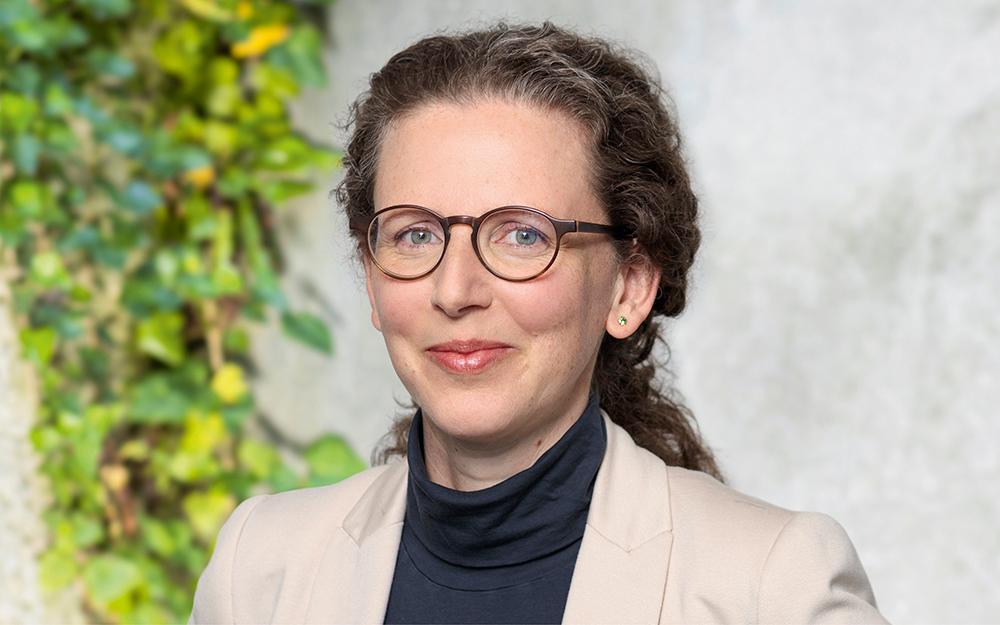 Sabine Perch Nielsen trägt eine Brille, einen schwarzen Rollkragenpullover und einen hellbeigen Blazer. 