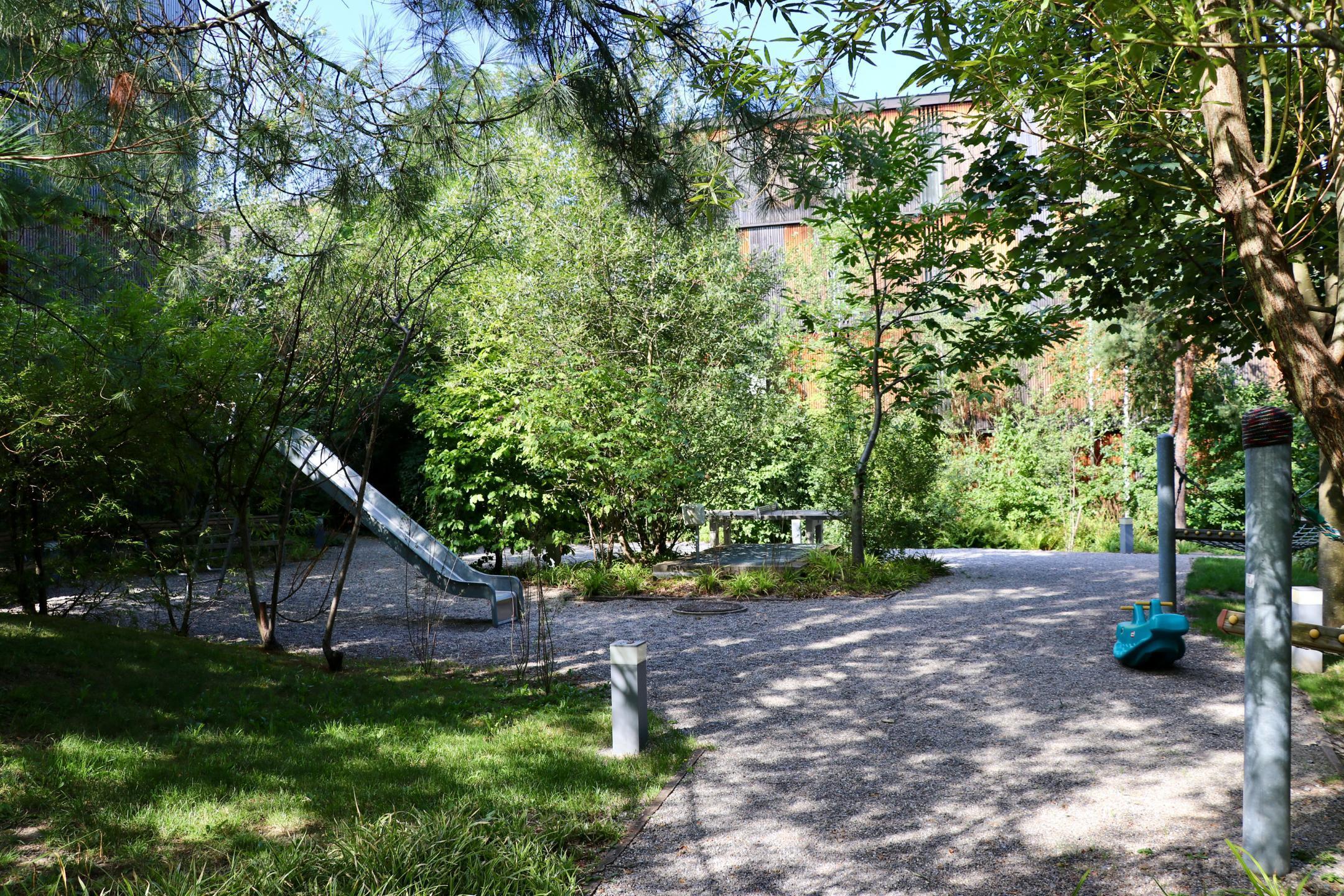 Naturnah gestaltete Fläche mit Spielgeräten, Ping-Pong Tisch und Bänken fördert die Aufenthaltsqualität in der Siedlung Escherpark in Zürich.