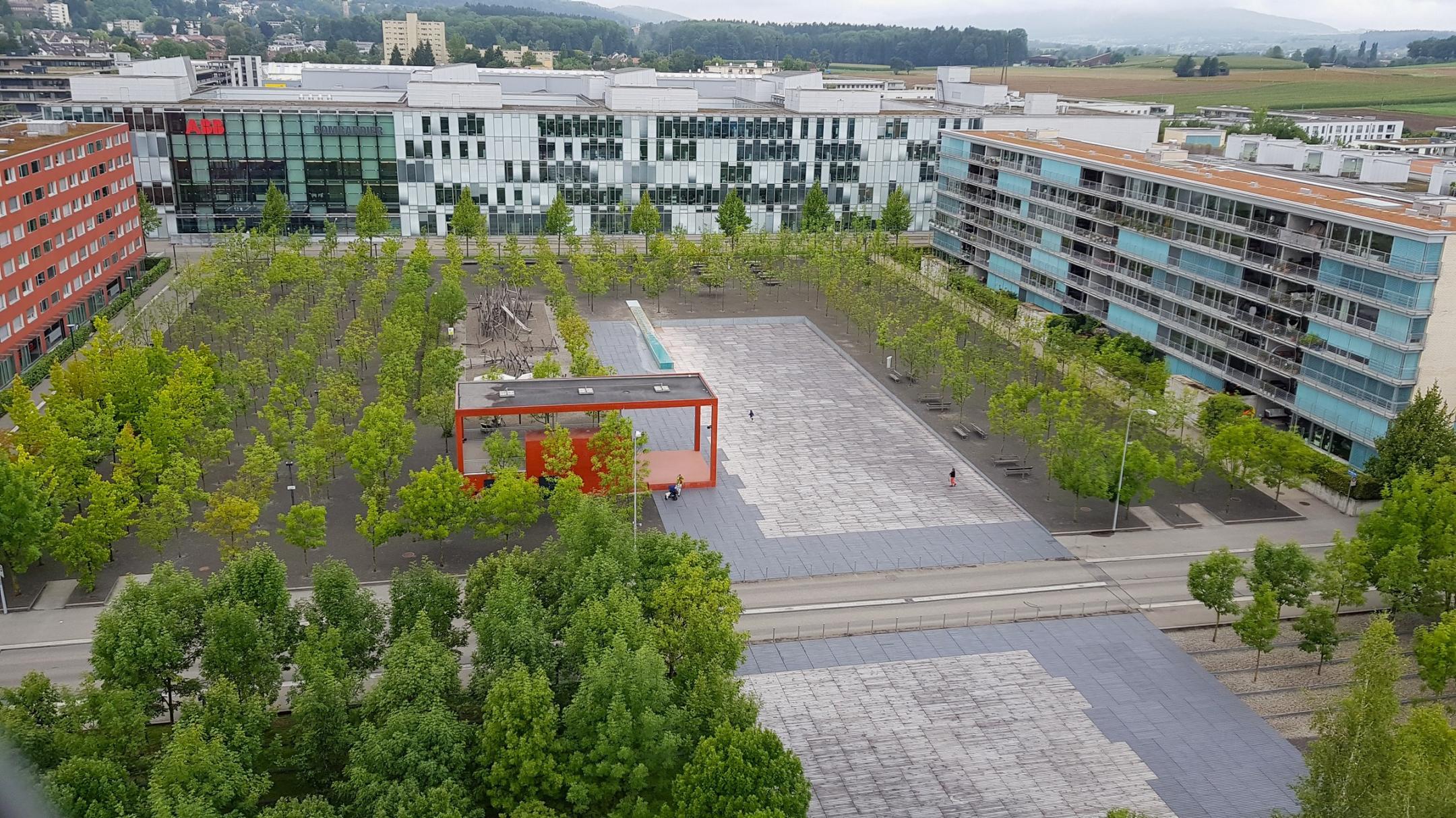 Ein Teil des Oerliker Parks in Zürich ist zu sehen, wo die Fläche entsiegelt ist. Es gibt Kiesflächen sowie Flächen, welche aus Holzrosten bestehen.