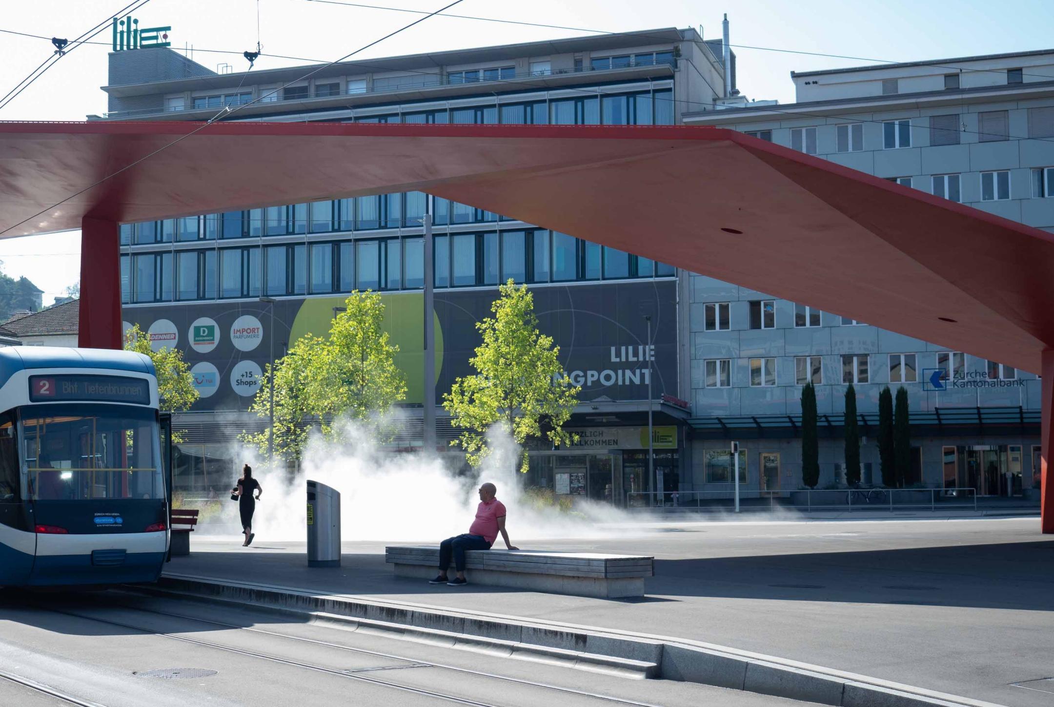 Schlieren Stadtplatz: Moderne Architektur spendet Schatten, und der Nebel aus dem Stadtbrunnen Kühle.