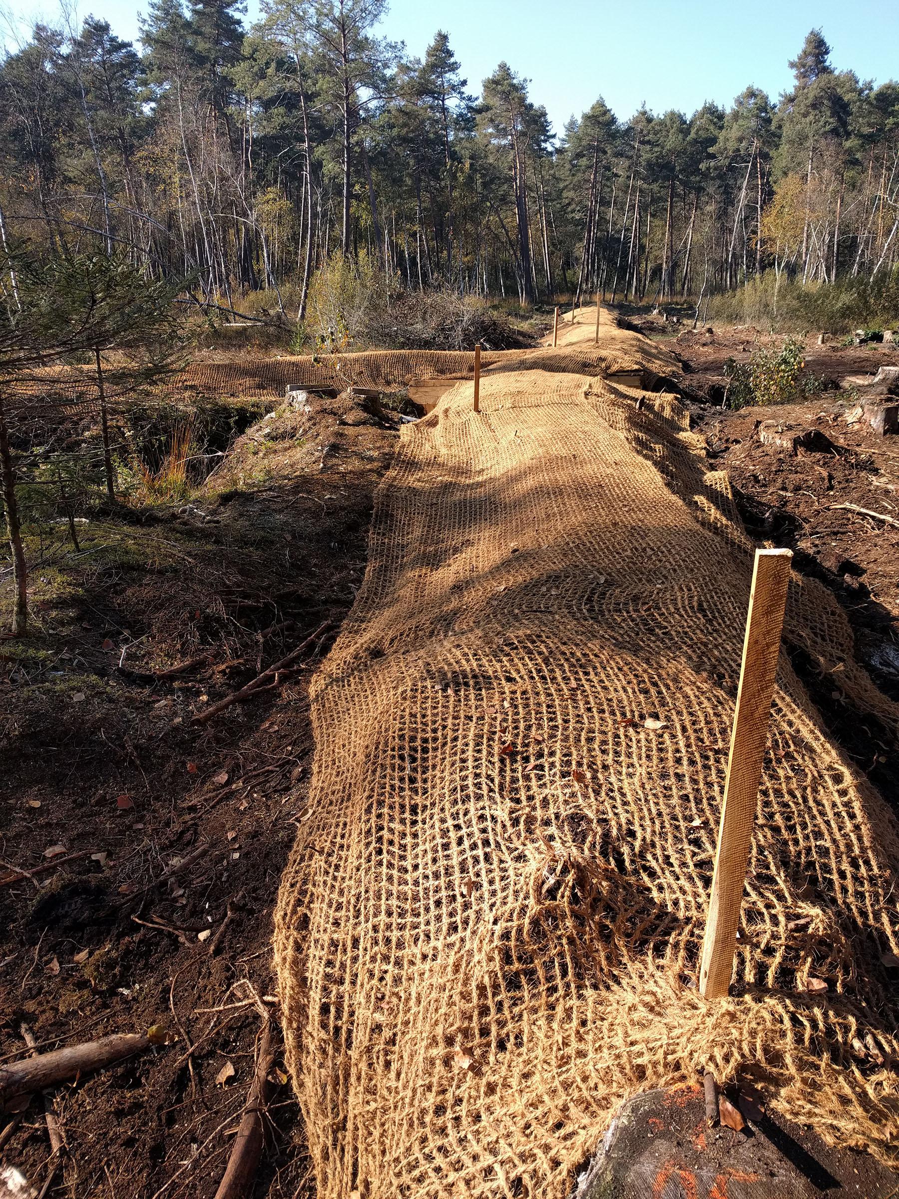 Mit einer Kokosmatte überzogener Hügel, unter der die Spundwand liegt