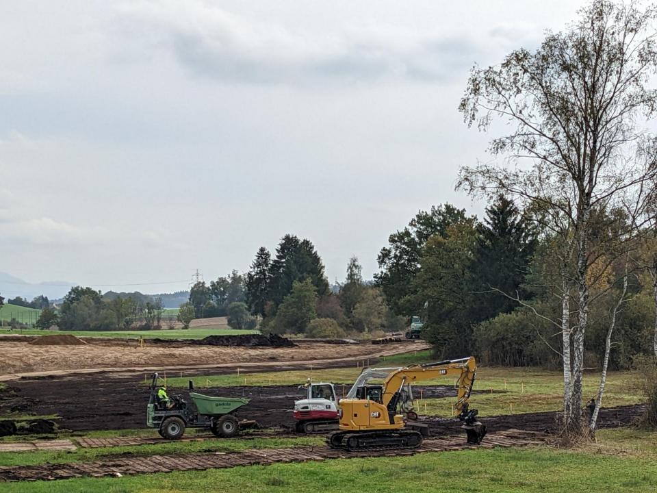 Zwei Bagger tragen Oberboden ab. Dieser wird anschliessend von einem Kipper abgeführt.