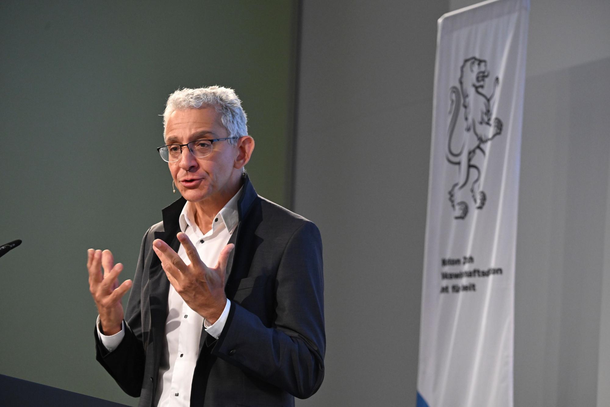 Arié Malz steht gestikulierend auf der Bühne.