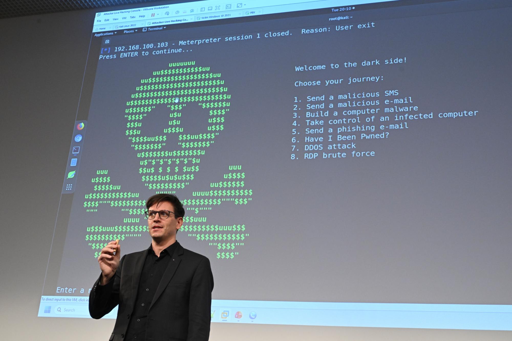 Ivano Somain steht auf der Bühne vor einem Hacker-Totenkopf.