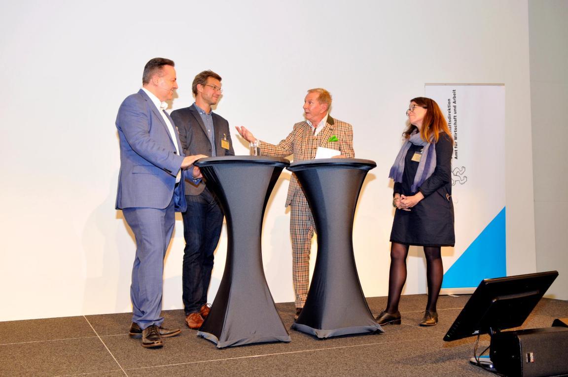 Edgar Spieler, Leiter Arbeitsmarkt im AWA,  Claudio Sedivy, Geschäftsführer Wildbiene und Partner, Katrin Hauser, Präsidentin von Scaling-4-good und Moderator Kurt Aeschbacher sind auf der Bühne in ein angeregtes Gespräch vertieft.